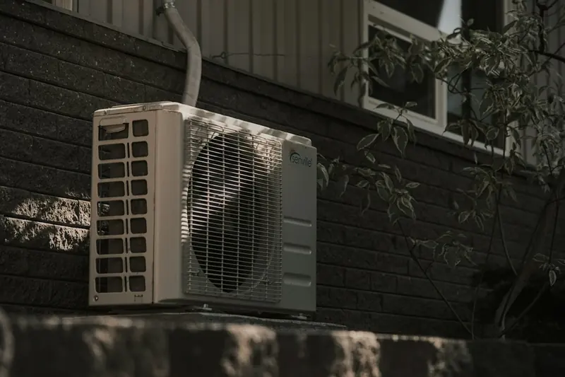 Thermopompe murale installée sur le mur de brique d'une maison