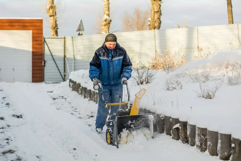 Ouvrier qui déneige une entrée à la souffleuse