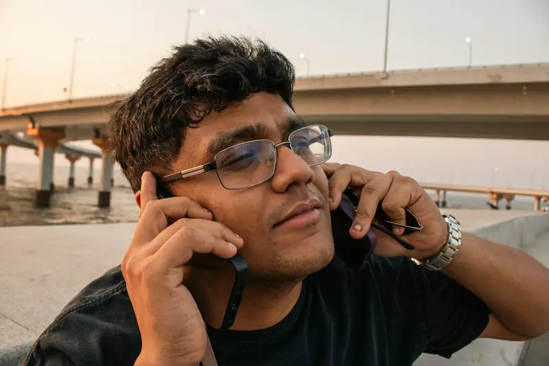 Homme qui tient un téléphone à chaque oreille pour prendre deux appels à la fois