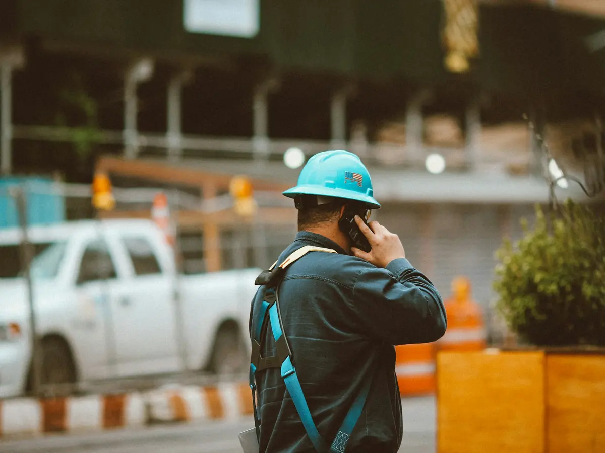 Entrepreneur casqué qui prend un appel sur son cellulaire, sur un chantier